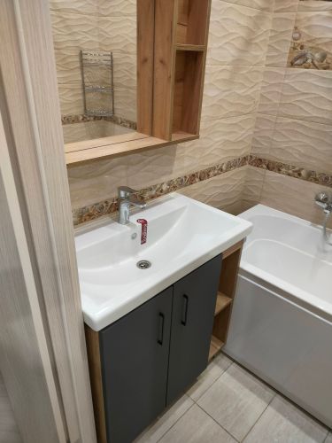 Установлен шкаф с зеркалом над раковиной в ванной комнате. Закреплены крепления, выровнена конструкция, проверена надежность фиксации. Завершены работы по монтажу.