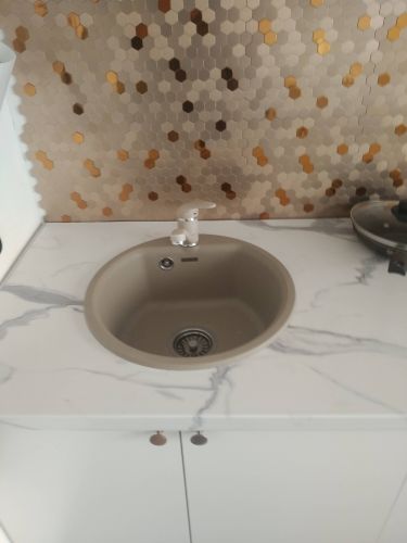 Изображена установленная раковина на столешнице с мраморным узором. Фон украшен гексагональной плиткой с золотистыми и бронзовыми акцентами.