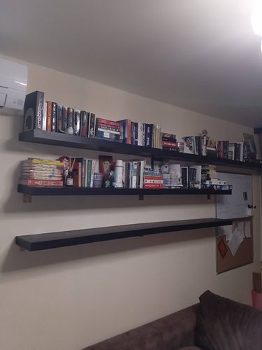 На стене установлены три полки, закрепленные надежно. Они ровно размещены и готовы для хранения книг и декора. Работа выполнена аккуратно и качественно.