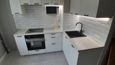 Установлены шкафы, закреплены фасады, смонтирована столешница, подключена мойка, встроена техника. Завершена отделка фартука плиткой, установлены ручки, проведено освещение.