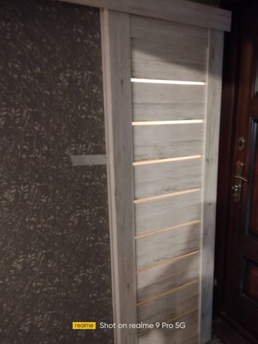 Установлена новая светлая дверь с горизонтальными вставками. Проведено крепление коробки, навешивание полотна, регулировка петель, монтаж наличников. Завершено оформление проема.