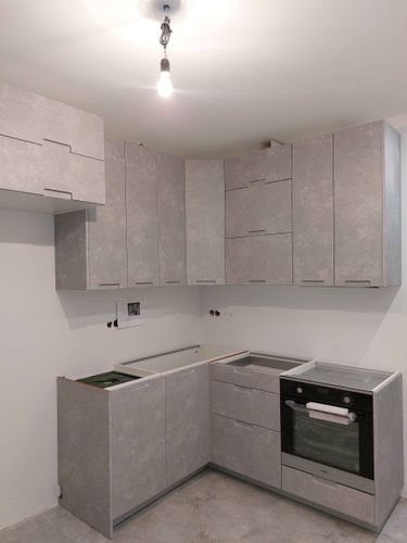 Установлены шкафы, закреплены фасады, вмонтирована бытовая техника, подготовлены места для столешницы. Проведены работы по выравниванию и фиксации элементов. Подготовка завершена.