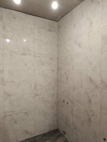 Стены облицованы керамическими плитами с мраморным узором. Швы аккуратно заделаны, поверхность ровная, без дефектов. Углы и стыки выполнены качественно, создавая цельный вид.