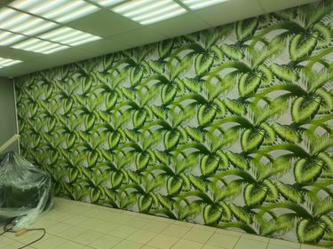 Завершена отделка: стены покрыты стеклохолстом с зелёными листьями, создающими эффект тропического леса. Поверхность ровная, швы незаметны, освещение подчёркивает текстуру.