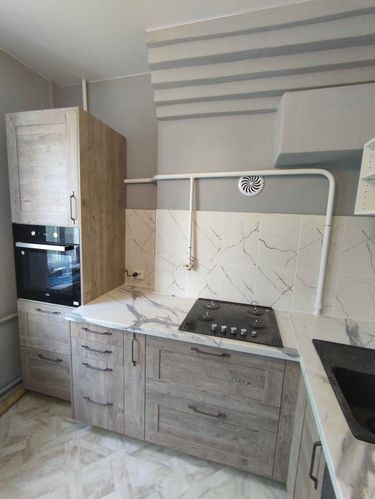 Установлены шкафы, закреплены фасады, смонтирована столешница, врезана варочная панель, подключена духовка, установлена мойка, выполнена облицовка стен плиткой.