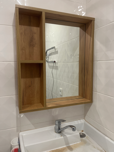 Установлено зеркало с деревянной рамой и полками над раковиной. Закреплено на стене, выровнено по уровню. Подключено освещение, проверена надежность креплений.