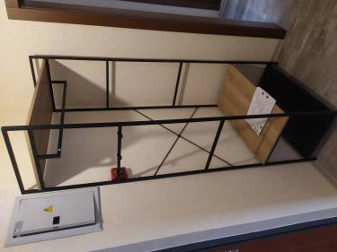 Собрана металлическая конструкция с полками и перекладинами. Установлены детали, обеспечивающие устойчивость и функциональность. Завершена установка всех элементов согласно инструкции.