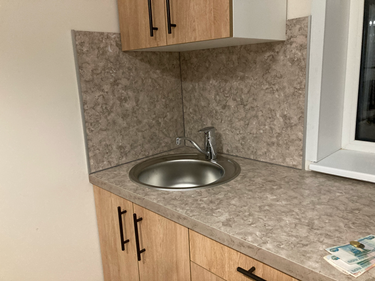 На изображении показан результат работы: столешница аккуратно подогнана под размеры, выполнен вырез для раковины, установлена мойка, все элементы плотно прилегают, создавая завершенный вид.