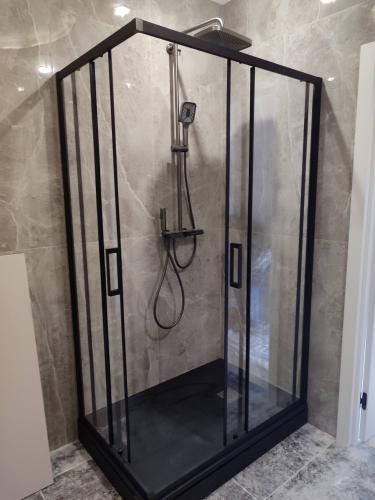 Установлен стеклянный уголок с черной рамой, закреплены двери, подключен смеситель и душевая лейка, герметично зафиксирован поддон, проверена работоспособность системы.