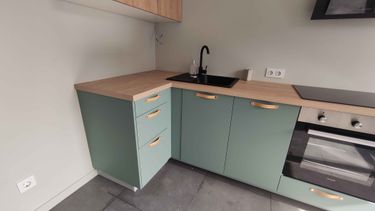 Установлены шкафы, закреплены фасады, смонтирована столешница, подключены раковина и варочная панель, установлены ручки, выровнены модули, завершена сборка.