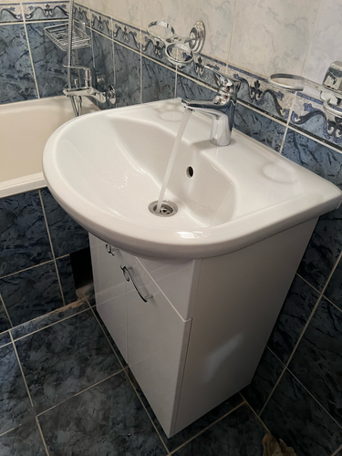 Изображен установленный новый кран на кухонной раковине. Проведены работы по демонтажу старого оборудования, монтажу нового, подключению коммуникаций и проверке герметичности соединений.