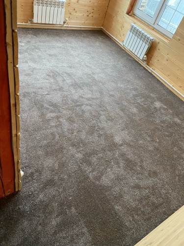 Покрытие ровно настелено на подготовленное основание, тщательно закреплено по периметру, без складок и неровностей, создавая уютную и аккуратную поверхность в помещении.