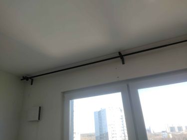 Установлен металлический карниз на потолок, закреплённый с помощью кронштейнов над окном, обеспечивая надежную фиксацию и готовность к использованию.