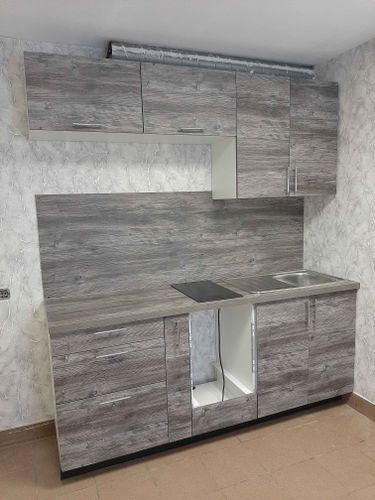 Установлены шкафы, закреплены фасады, смонтирована столешница, врезана мойка, подключена варочная панель, выполнена отделка стен панелями, установлены ручки.