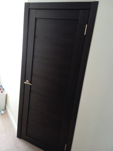 Установлена деревянная створка, закреплены петли, врезана ручка, отрегулированы зазоры, проверена плавность открывания, завершена отделка наличниками, обеспечена надежная фиксация конструкции.