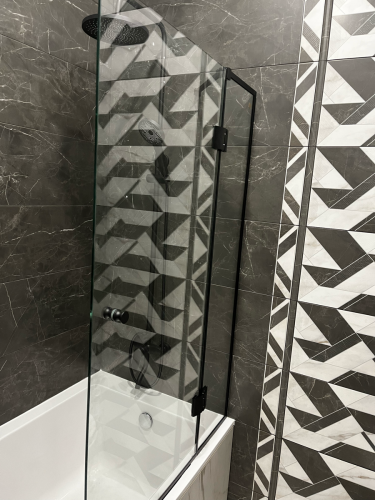 Изображена стеклянная перегородка в ванной, закрепленная на стене. Установлены крепления, обеспечивающие устойчивость и безопасность конструкции. Завершенный монтаж гармонично вписывается в интерьер.