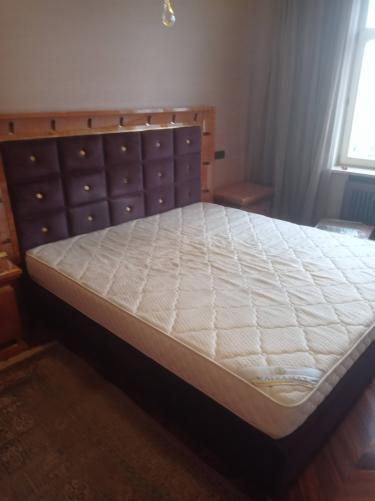 Собрана двуспальная кровать: установлено изголовье, закреплены боковые панели, уложен матрас. Все элементы надежно соединены, конструкция устойчива, готова к использованию.