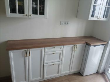 На кухне установлена новая столешница из ДСП. Поверхность аккуратно закреплена на шкафах, стыки ровные, без зазоров. Все элементы подогнаны точно, обеспечивая эстетичный вид и функциональность.