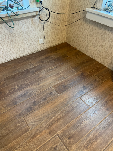 На полу уложены панели, создающие ровное и эстетичное покрытие. Все элементы аккуратно подогнаны, швы плотно соединены, поверхность выглядит гладкой и завершенной.