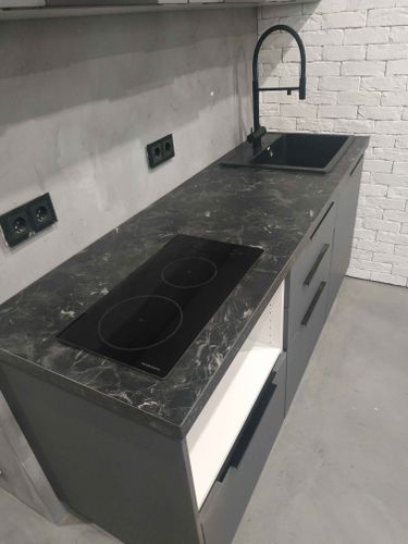 Выполнена установка кухонной поверхности: произведены точные вырезы под варочную панель и мойку, обеспечена идеальная подгонка к шкафам и стене, завершена отделка краев.