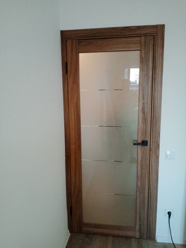 Установлена новая деревянная дверь с матовым стеклом. Закреплены петли, ручка и замок. Проведена подгонка коробки, обеспечена плавная работа створки. Завершена отделка откосов.