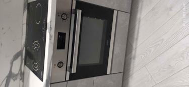 На изображении установлена варочная панель и духовой шкаф в кухонный гарнитур. Поверхность подключена к электросети, все элементы встроены и готовы к использованию.