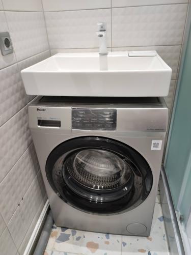 Установлена раковина над стиральной машиной, подключены трубы для подачи холодной и горячей воды, обеспечен слив. Компактное размещение сантехники в ванной комнате завершено.