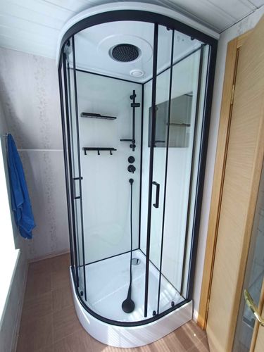 Завершена установка новой душевой конструкции с прозрачными стенками и черными элементами. Обновлены коммуникации, добавлены полки для удобства. Пол облицован плиткой.