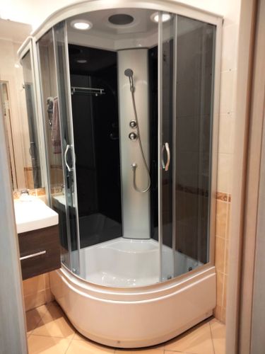 Установлена современная душевая конструкция с герметичными стеклянными панелями, подключены водопроводные коммуникации, смонтирован поддон, закреплены дверцы, проверена функциональность системы.