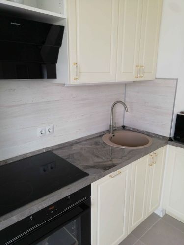 Установлена кухонная поверхность с вырезами для варочной панели и мойки. Все элементы аккуратно подогнаны, обеспечивая стильный и функциональный вид.