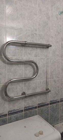 Монтаж завершён: закреплён новый водяной полотенцесушитель на кафельной стене, подключены трубы, проверена герметичность соединений, обеспечена надёжная фиксация.