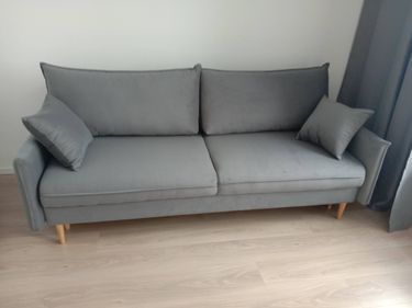 Собран новый диван: установлены ножки, закреплены подлокотники, подушки размещены. Все элементы соединены, конструкция устойчива, готова к использованию.