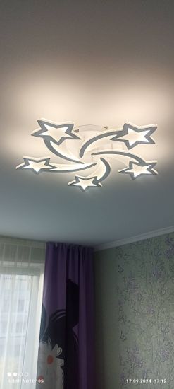 Закреплен светильник на натяжной поверхности, подключены провода, проверена работа. Установлена декоративная конструкция с элементами в форме звезд, обеспечивающая равномерное освещение.