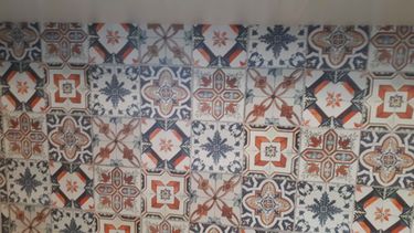 Установлены шкафы, закреплены фасады, смонтирована столешница из ДСП, подключены мойка и техника, выполнена облицовка стен декоративной плиткой с узорами.