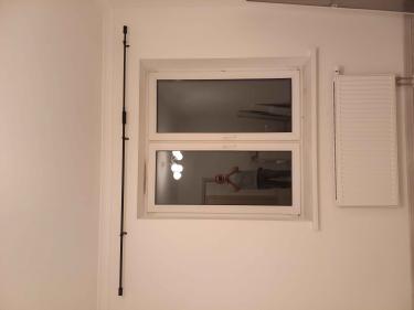 На стене над окном закреплен металлический карниз для штор. Установлены крепления, обеспечивающие надежность конструкции. Работа завершена, все элементы надежно зафиксированы.