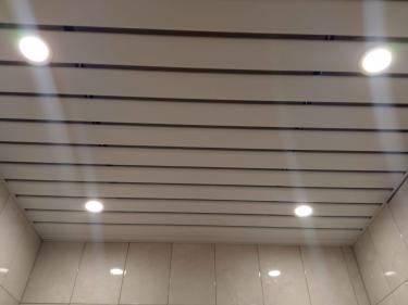 Установлены панели с равномерными промежутками, встроены светильники, обеспечивающие освещение. Поверхность ровная, аккуратная, без видимых дефектов. Завершено оформление потолка.