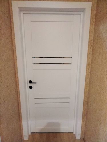 Установлена белая дверь с горизонтальными вставками, смонтирована коробка, закреплены петли, врезана ручка, выполнена подгонка полотна, обеспечена плавность закрытия.