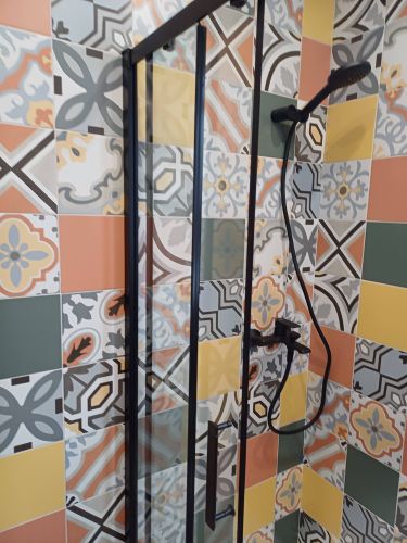 Изображение демонстрирует завершенную установку душевого оборудования в ванной комнате с яркой плиткой. Смеситель и душевая лейка закреплены на стене, обеспечивая функциональность и стиль.