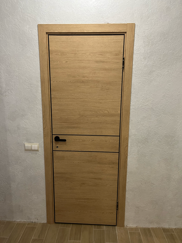 Деревянная створка установлена, петли закреплены, ручка смонтирована, замок вставлен, коробка выровнена, наличники прикреплены, зазоры устранены, поверхность обработана, работа завершена.