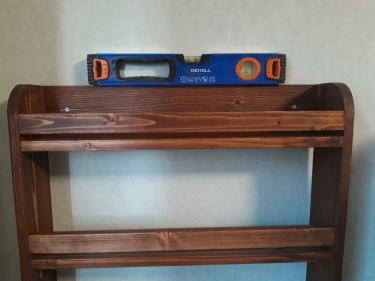 Деревянная полка надежно закреплена на стене. Использован уровень для точного выравнивания. Шурупы вкручены, обеспечивая устойчивость конструкции. Работа завершена аккуратно и качественно.