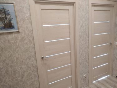 Установлена светлая дверь с горизонтальными вставками, врезаны замок и ручка, закреплены петли, отрегулировано полотно, оформлен проем, выполнена отделка наличниками.