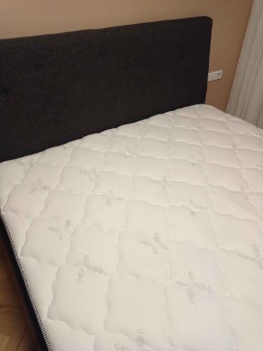 Собрана двуспальная кровать: установлено изголовье, закреплены боковые панели, собран каркас, уложен матрас. Все элементы надежно зафиксированы, конструкция устойчива и готова к использованию.