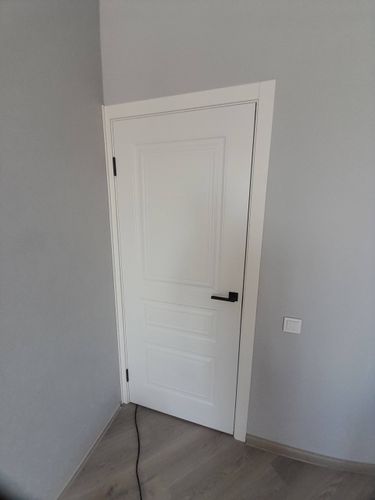 Установлена новая белая дверь с ручкой и петлями. Проведена подгонка по размеру проема, закреплены наличники. Завершено аккуратно, без зазоров, обеспечена плавность открывания.