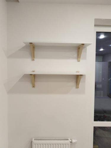 На стене установлены две полки с деревянными креплениями. Каждая конструкция надежно закреплена, обеспечивая устойчивость и функциональность. Работа выполнена аккуратно и качественно.