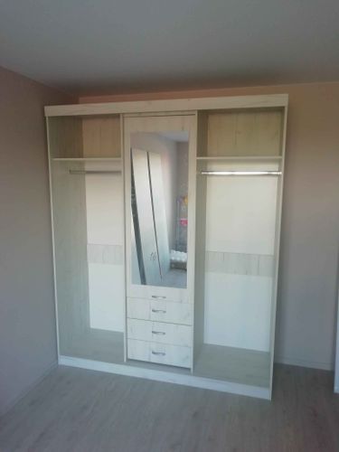 Собран шкаф с зеркалом, полками, выдвижными ящиками и вешалками для одежды. Установлены все элементы, обеспечена устойчивость и функциональность конструкции.