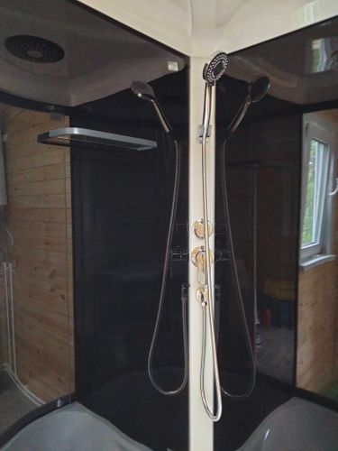 Установлена современная душевая конструкция с черными стенками и хромированными элементами. Проведены работы по монтажу, подключению водоснабжения и герметизации швов.