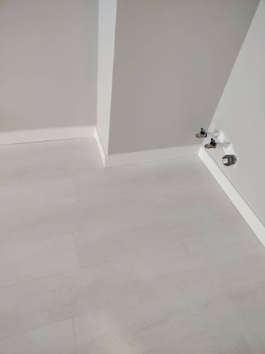 Установлены новые плинтусы вдоль стен, обеспечивая аккуратное примыкание к полу и углам. Все элементы подогнаны, создавая завершенный вид интерьера.