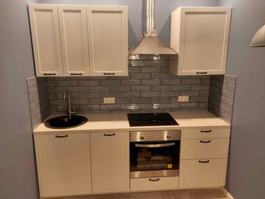 Установлены шкафы, смонтирована столешница, врезана мойка, подключена вытяжка, закреплены ручки, уложена плитка на фартук, подключены розетки, установлена варочная панель и духовой шкаф.