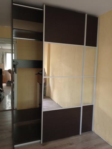 Установлен шкаф с раздвижными дверями, зеркальной панелью и полками. Сборка завершена, элементы выровнены, конструкция устойчива, функциональна, гармонично вписывается в интерьер.