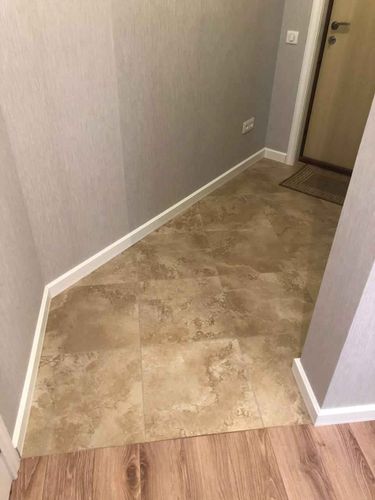 Угловое соединение стен и пола оформлено белым плинтусом, аккуратно закрепленным по периметру. Завершённый вид интерьера подчёркивает плавный переход между покрытиями.